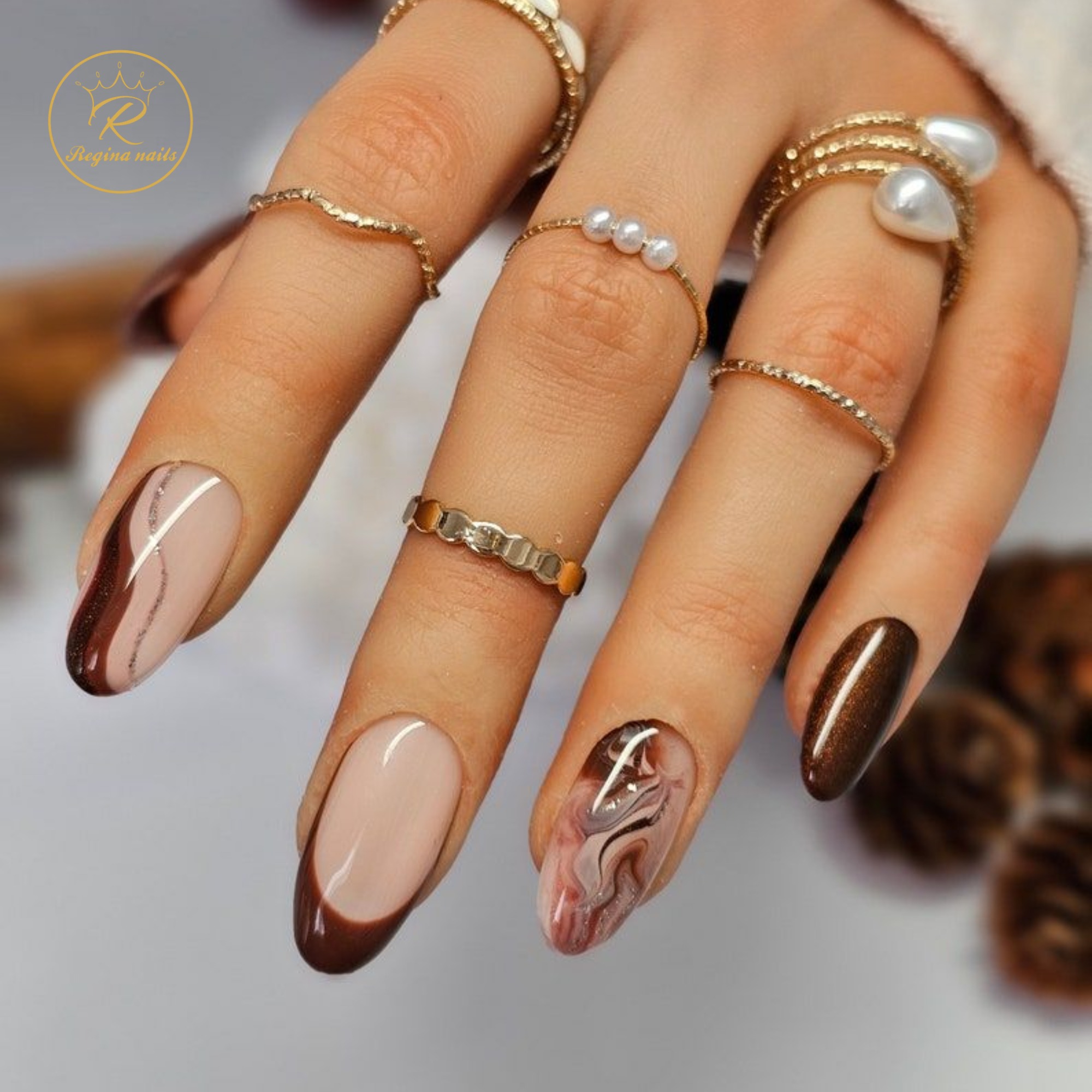 Almond nails with brown French tips and marble accent design