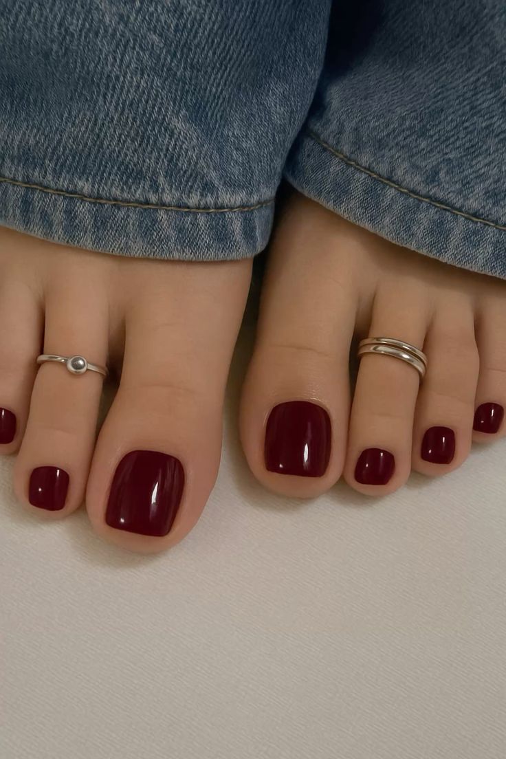 Toe nails painted in dark red gel polish