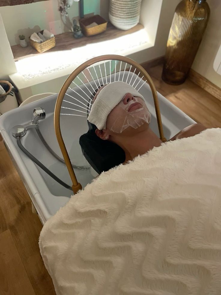 Client enjoying a relaxing facial treatment with hot towel therapy and hydrating mask in a spa setting.
