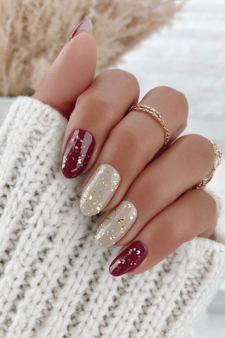 Red and nude almond nails decorated with gold foil flakes.